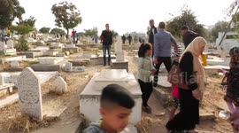 Palestinians visit the graves of their relatives at a cemetery during the first day of Eid al-Fitr holiday which marks the end of the Muslim holy month of Ramadan