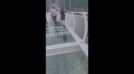 Vietnamese tourists walk on the world's longest glass bridge built on a cliff in northern Vietnam