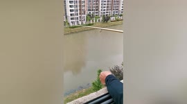 Quarantined Shanghai resident who lives next to river fishes from his balcony