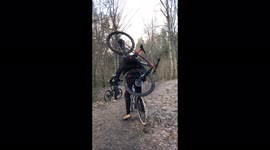 Bike rider carries a bike on his back while going down the trail with his dog next to him