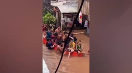 Delighted youngsters splash across flooded street in rescue boat