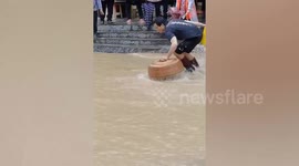 Excited locals jump into flooded road with baskets and nets to catch fish in China