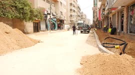 Palestinian workers work to renew a damaged of al-Wehda Street which was hit by Israeli strikes during the recent 11-day conflict between Israel and Hamas last year
