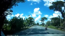 Daredevil stands on motorcycle while speeding down a road in Thailand