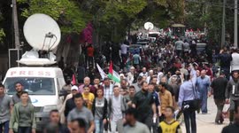 Palestinian wave national flags as they march in a rally marking the 74th anniversary of the
