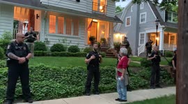 An elderly woman holds up a coat hanger in front of Brett Kavanaugh’s house.