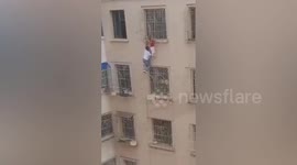 Man climbs five floors to save girl hanging from window in China