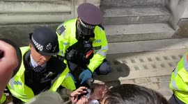 Police hold down a protester trying to glue herself to building during Shell’s annual general meeting