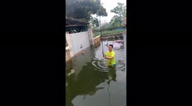 Vietnamese man deals with the stress of a flooded home by fishing in the floodwaters