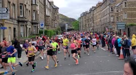 Runners of the 2022 Edinburgh Marathon running through the streets of Old Town Edinburgh