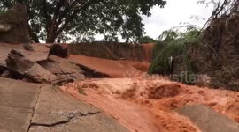 Reservoir overflows sending torrents of muddy water gushing through fields in Thailand