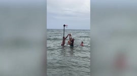 Beachgoers play basketball game in waist-deep seawater