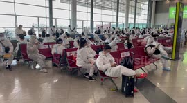 Hundreds of Chinese tourists wear matching hazmat suits to board plane