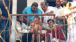 Crowds watch on as toddler with head stuck in between metal bars is rescued