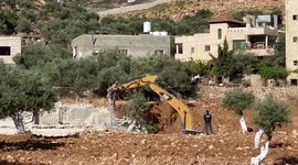 An Israeli bulldozer demolishes a Palestinian building under construction in the West Bank city of Bethlehem