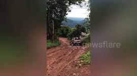 Pickup truck struggles across rugged dirt road drenched by heavy rain