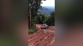 Pickup truck struggles across rugged dirt road drenched by heavy rain