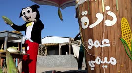 Palestinian corn vendor Muhammad Mukhaimer dressed in a mouse costume, enlivens his stall named