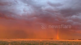 Colorful orange sunset double rainbow with lightning and rain curtains near Kirk, Colo.