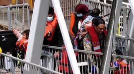 Vulnerable migrants disembark in Dover: child gives thumbs-up as she happily leaves Border Force vessel