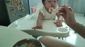 Funny actions of a baby girl rejecting food from her mom
