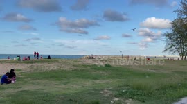 Beachgoers fly kites on windy evening in Narathiwat, southern Thailand
