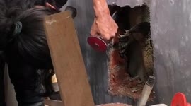 Rescuer smashes the wall to save a monitor lizard trapped in the gap