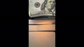 $100 bills being counted slowly on a money machine in slow motion