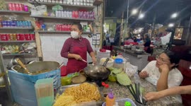 Woman cooks Khmer noodles street food at market in Cambodia