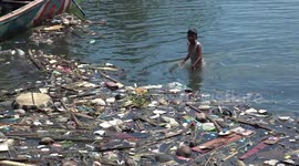 Children swim amongst islands of litter floating on sea off Indonesian coast