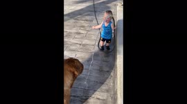 Adorable baby boy can't stop giggling while playing with his dog with a hose pipe