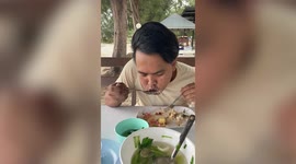 Tourist struggles to eat lunch while being battered by strong winds from the sea