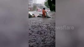 Motorcycle rider battles through flash flood in Cambodia