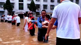 Firefighters and parents stand in deep water to transfer children out of flooded kindergarten