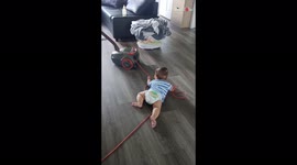 ' Toddler enjoys a free ride by grabbing the vacuum cleaner cord
'