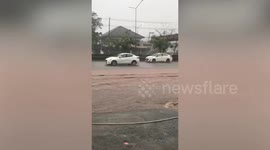 Drivers battle through flooded road during monsoon season storm in northeast Thailand