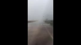 The truck driver steers the vehicle away from the violent tornado