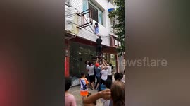 Residents save girl hanging out of first-floor window in China