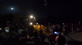 Sri Lankan anti-government protesters use a construction excavator to unsuccessfully break police barricades near Parliament