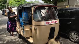 Sri Lankans push a tuk-tuk filled with domestic gas cylinders