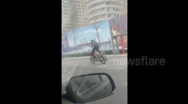 Motorcyclist rides fast while standing on scooter