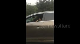 Woman addicted to karaoke sings with microphone while she's driving