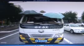 Drivers hold umbrellas to keep rain out after losing front window