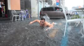 Man in Speedos swims on a road in flood water in Sicily
