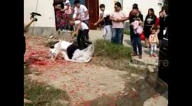 Groom carries bride, trips over wedding dress, falls on top of her