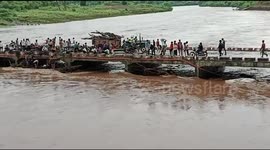 Despite a raging and swelling river, villagers picking wood from it