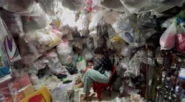 Woman sits in market stall surrounded by motorcycle stickers