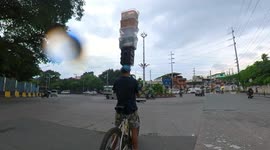 Amazing vendor on bicycle balances six trays on head
