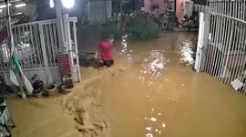 Clumsy resident trips and falls flat in muddy water while pulling cart through flood