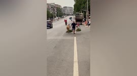 Vendor expertly balances carrying pole on shoulders as he transports vegetables along street